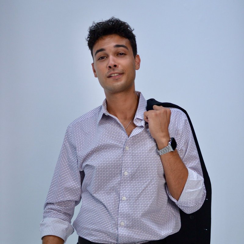 Aaron Fowler, founder of Aamplify, waist-up portrait in a patterned shirt with a jacket over his shoulder